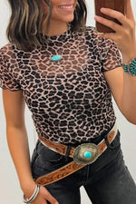 Person wearing a leopard print top and black pants with a belt, holding a phone.