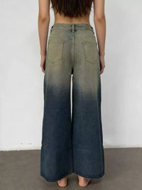 Person wearing a pair of wide-leg jeans with a gradient effect against a plain background