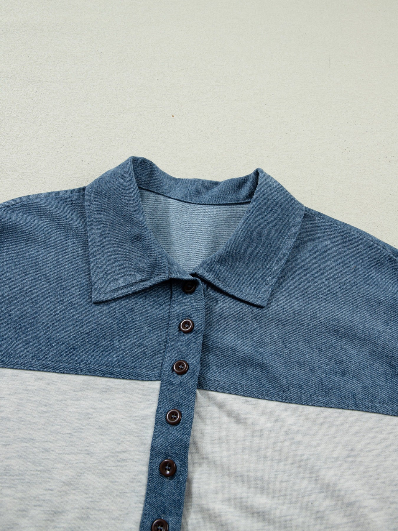 Close-up of a blue and gray polo shirt with a collar on a light gray background