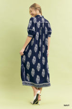 Woman wearing a navy dress with white floral pattern on a light green background