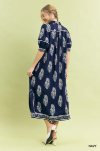 Woman wearing a navy dress with white floral pattern on a light green background