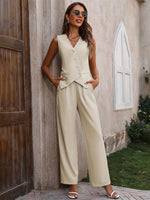 Woman in a beige suit standing against a stone wall.