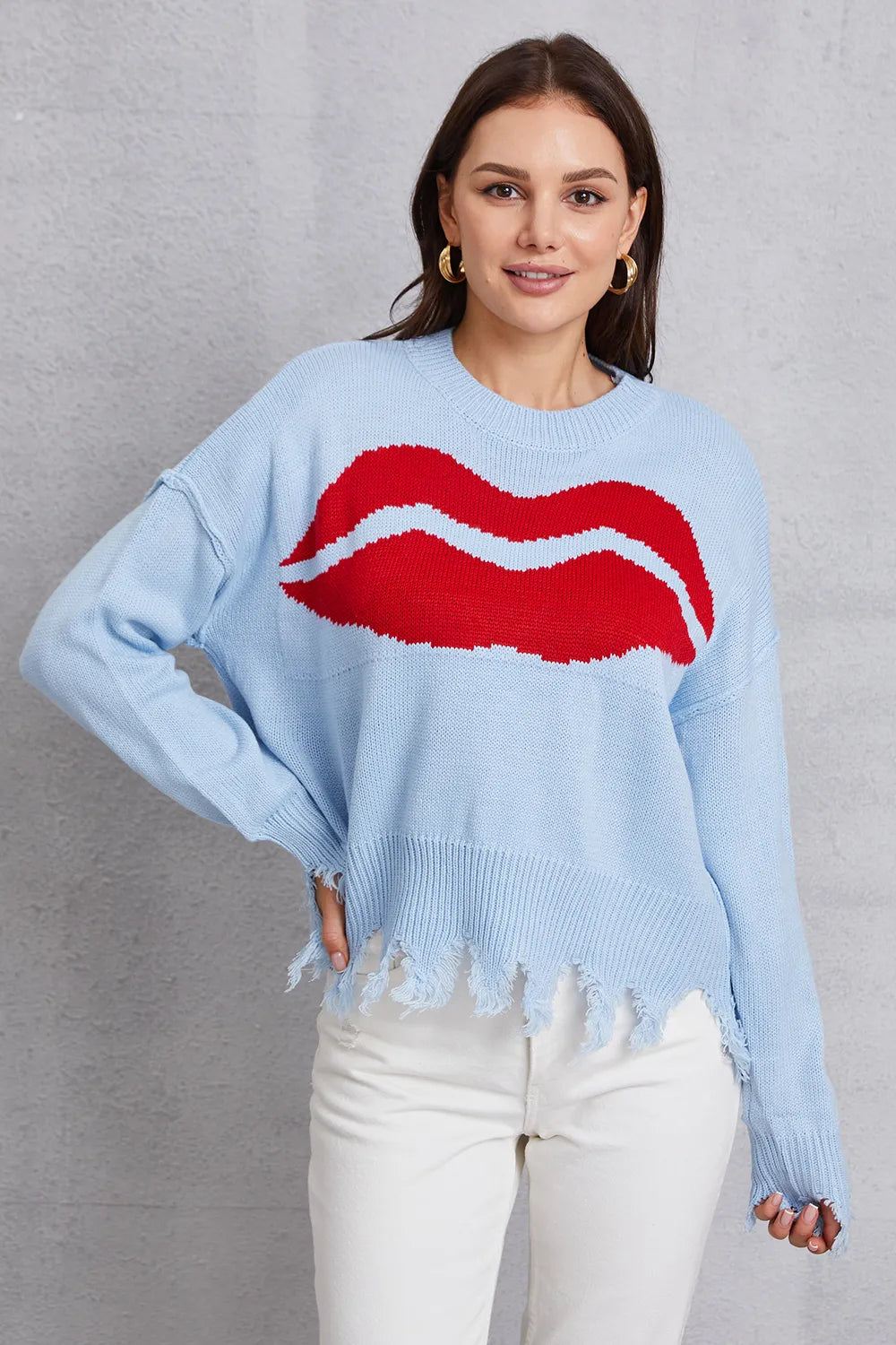 Woman wearing a light blue sweater with red lips design on a gray background