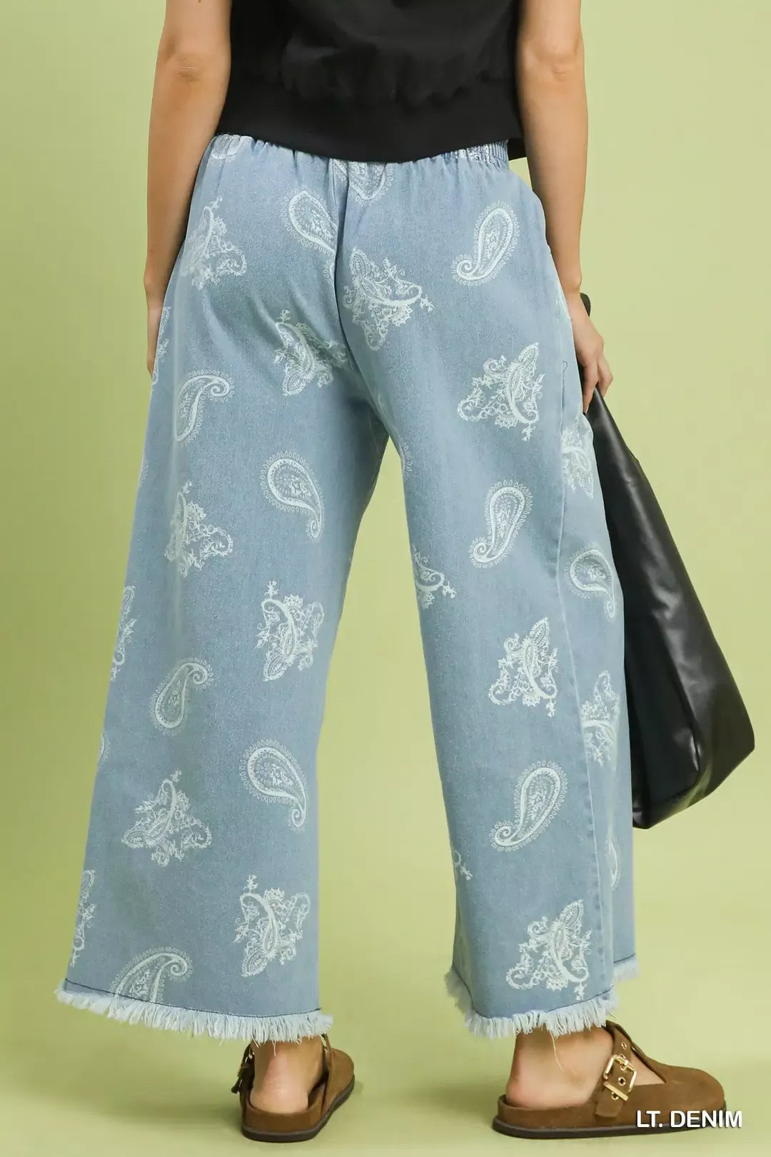 Light blue denim pants with white patterns worn by a person on a green background