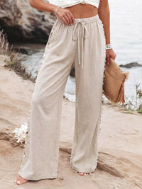 Person wearing beige wide-leg pants with a beach background