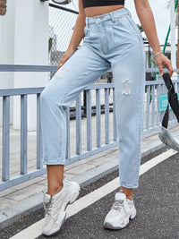 Person wearing light blue jeans and white sneakers on a street.
