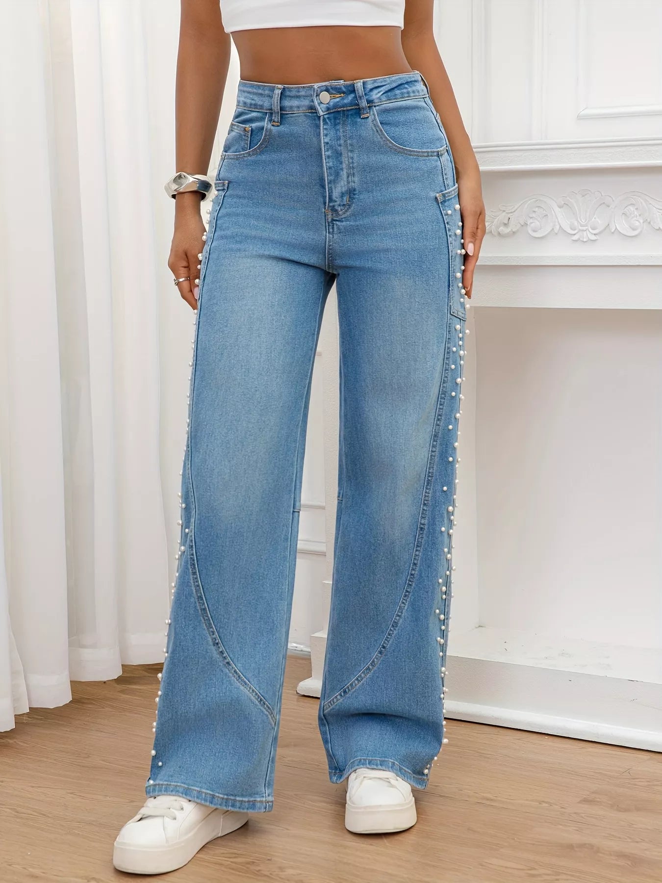 Person wearing high-waisted blue jeans with decorative elements indoors.