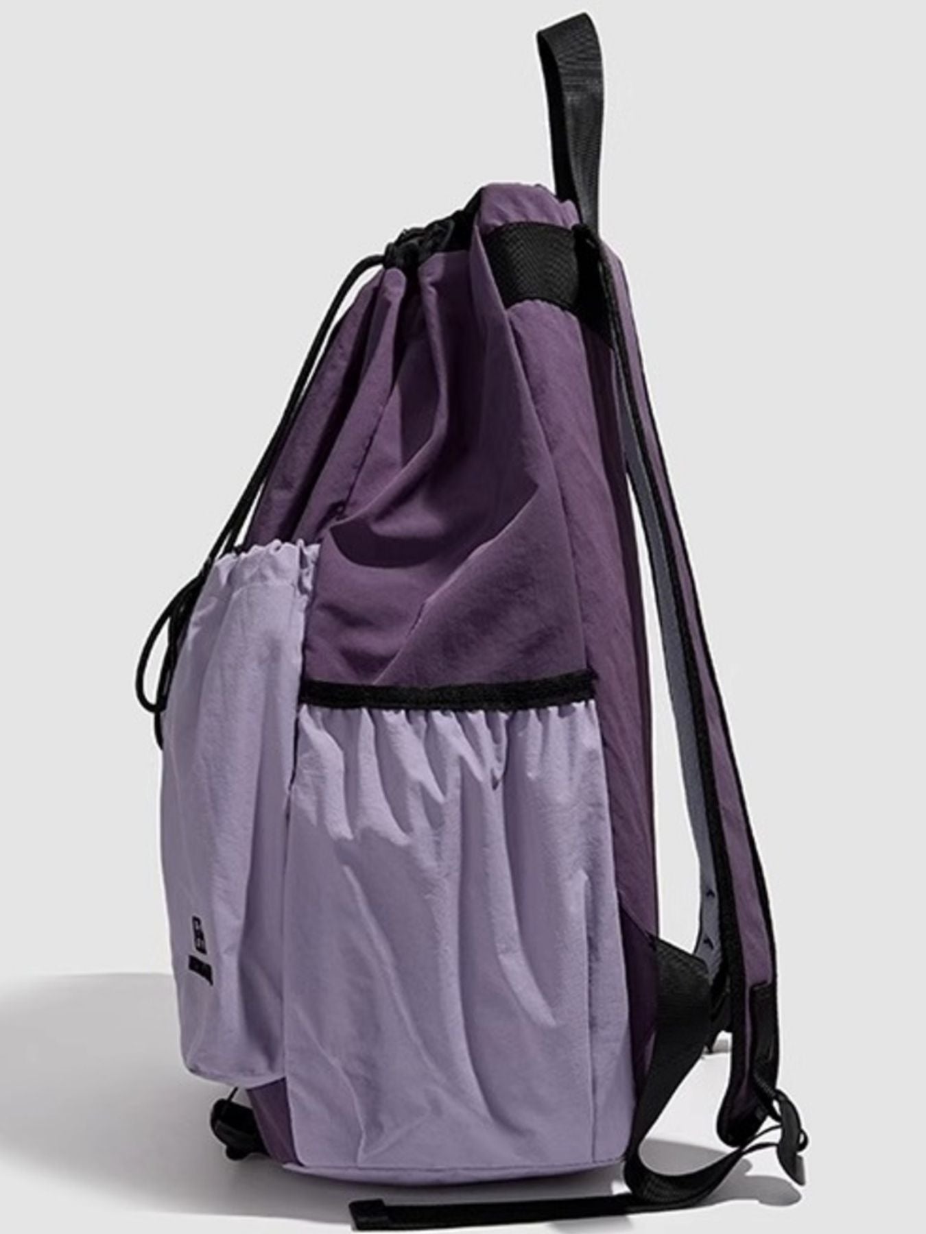 Purple drawstring bag with a smaller compartment on a light gray background
