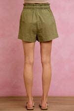 Person wearing green shorts against a pink background