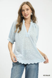 Woman wearing a light blue poncho with scalloped edges on a white background