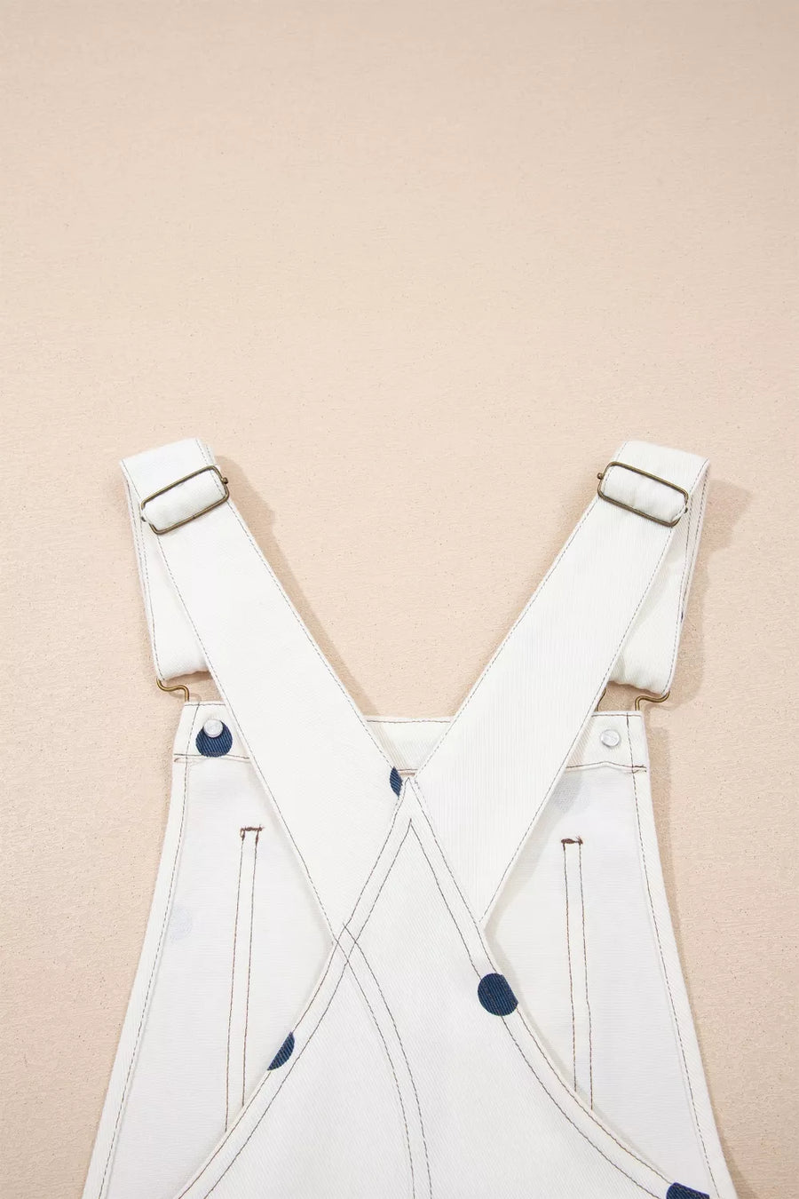 White overalls with blue buttons on a beige background