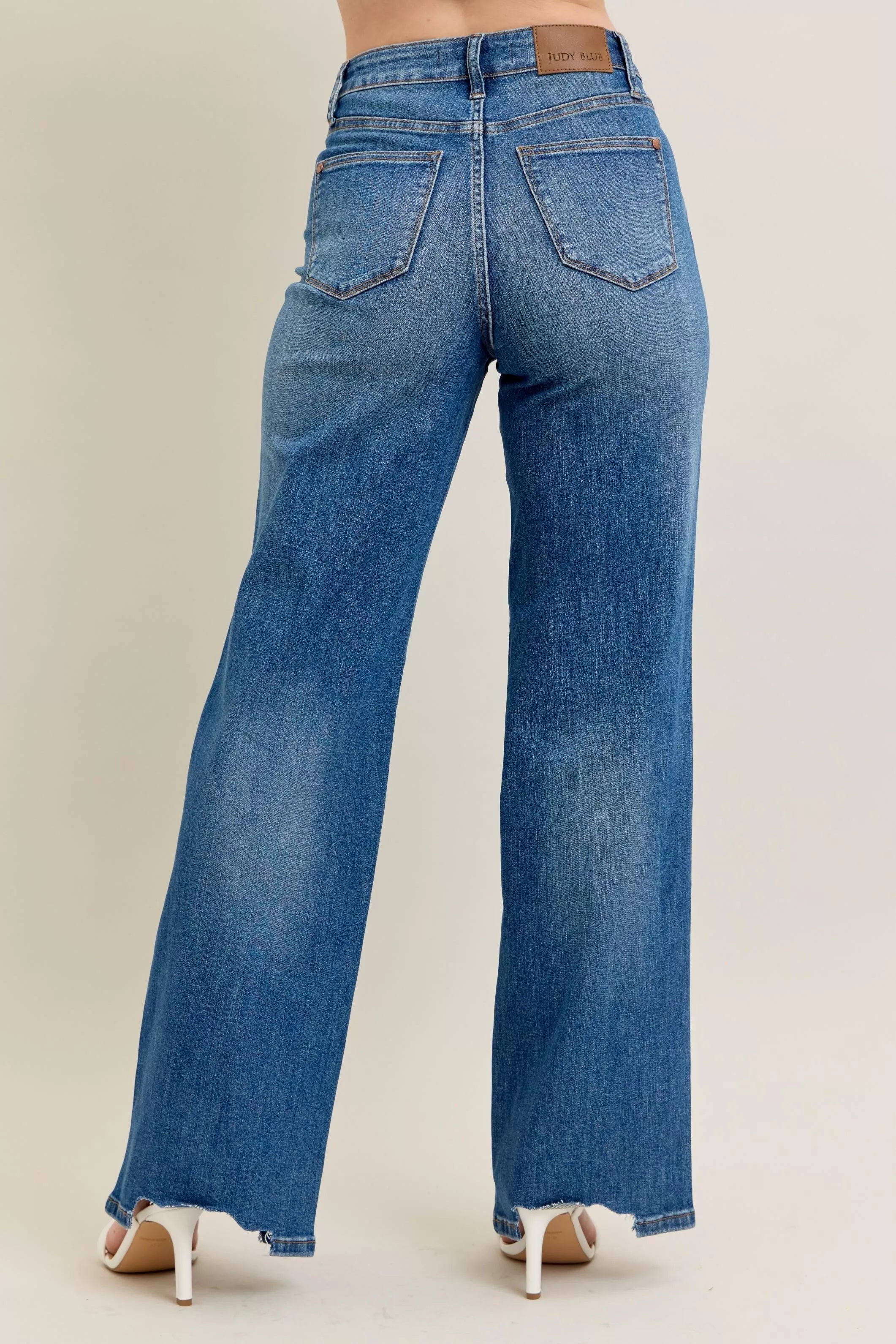 Blue jeans worn by a person on a beige background