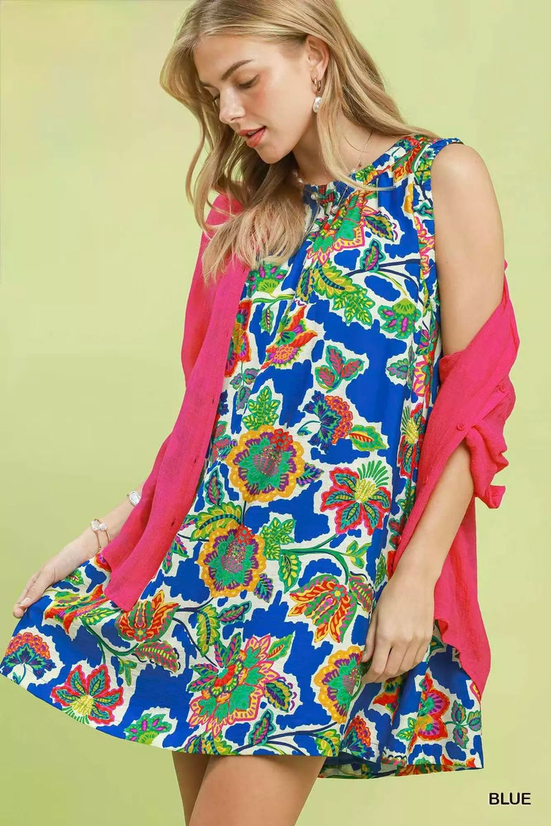 Woman wearing a colorful floral dress with a pink cardigan on a light green background