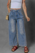 Person wearing blue wide-leg jeans and a white crop top on a gray background
