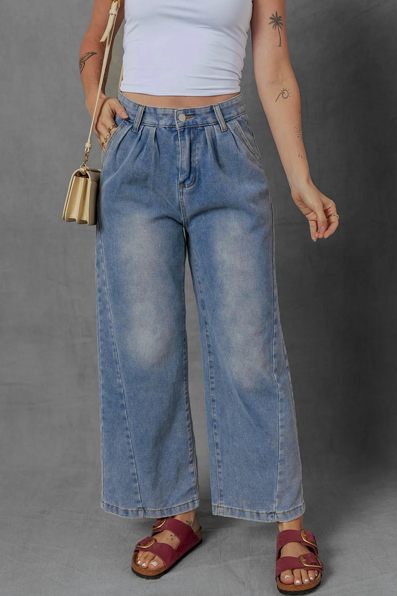 Person wearing blue wide-leg jeans and a white crop top on a gray background
