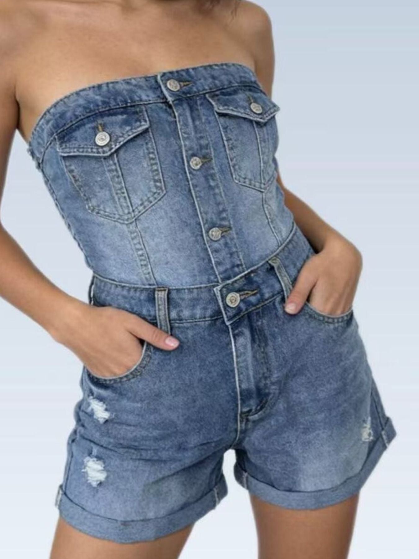 Denim romper with rolled-up shorts on a plain background