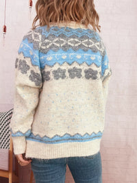 Person wearing a patterned sweater with blue and gray design against a light background