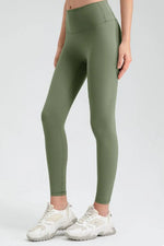Person wearing olive green leggings with white sneakers on a light gray background