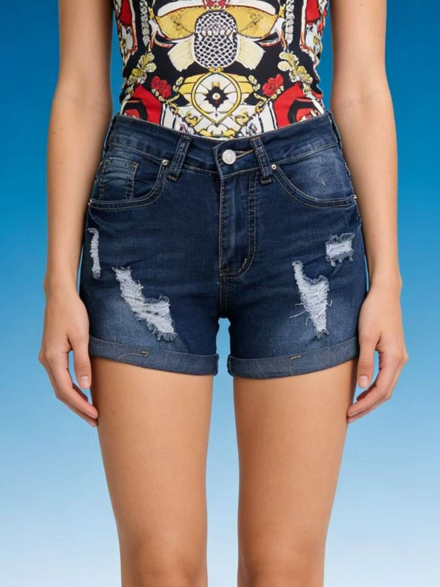 Person wearing a colorful top and blue denim shorts on a gradient background