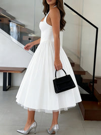 Woman in a white dress holding a black handbag in an indoor setting