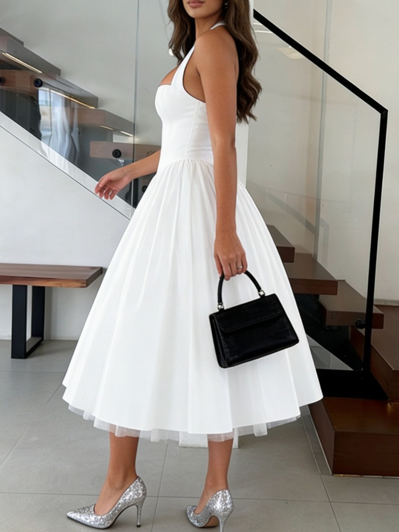 Woman in a white dress holding a black handbag in an indoor setting