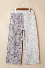 Floral-patterned pants on a hanger against a beige background