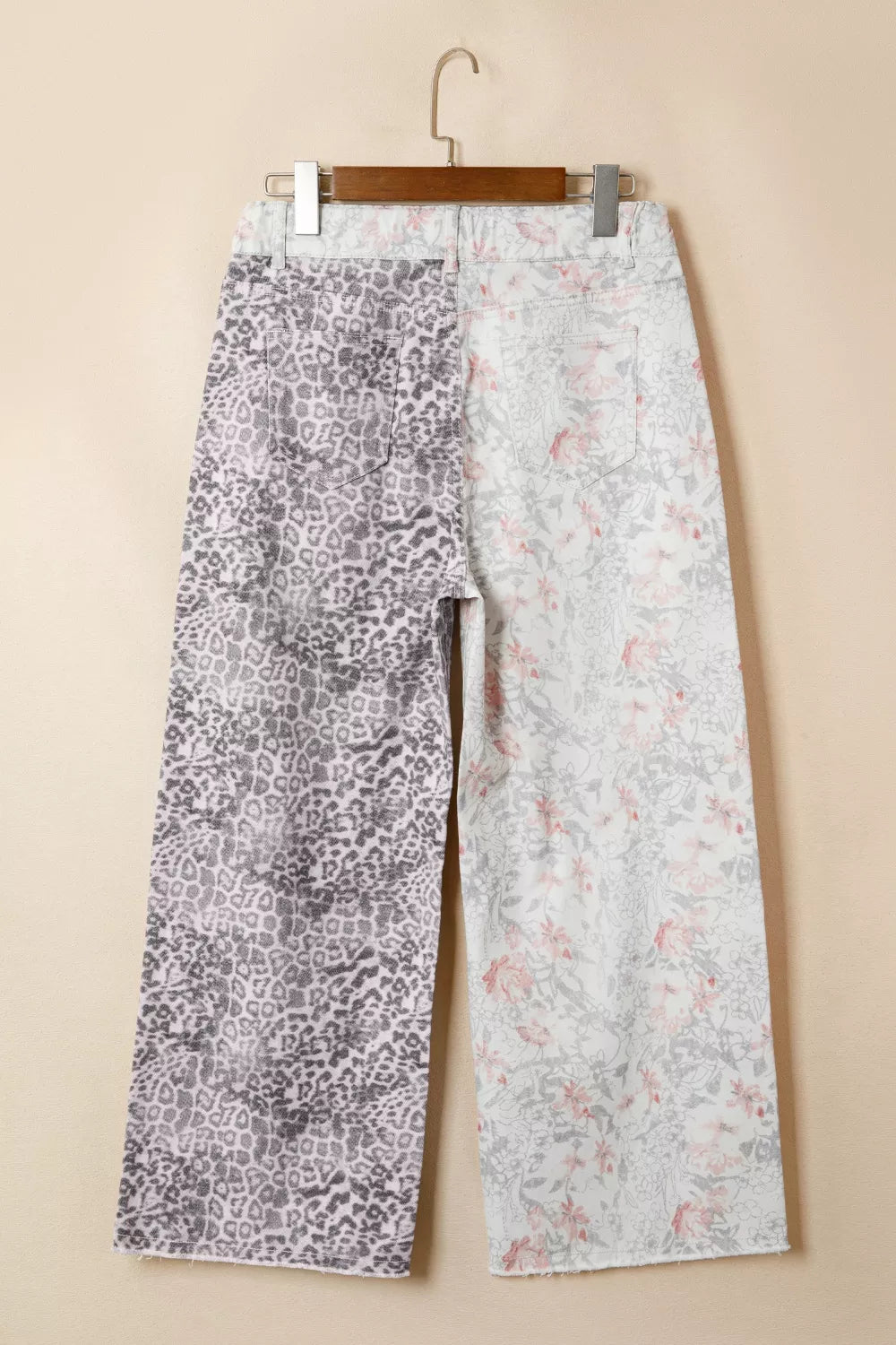 Floral-patterned pants on a hanger against a beige background