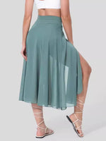 Person wearing a green skirt with a slit on a plain background