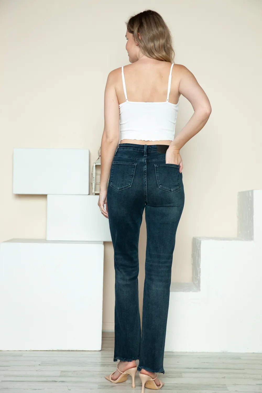 Woman wearing dark blue jeans and a white top in a minimalistic setting