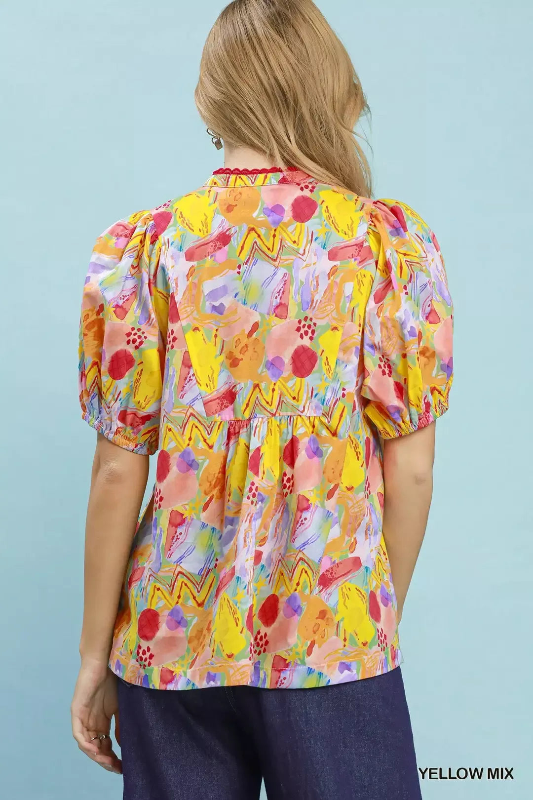 Woman wearing a colorful blouse with floral pattern against a light blue background
