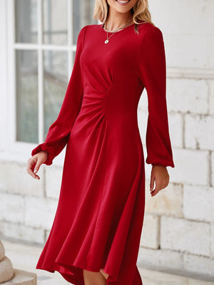 Woman wearing a red dress with long sleeves in an outdoor setting.