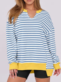 Blue and white striped long-sleeve top with yellow accents worn by a person on a plain background