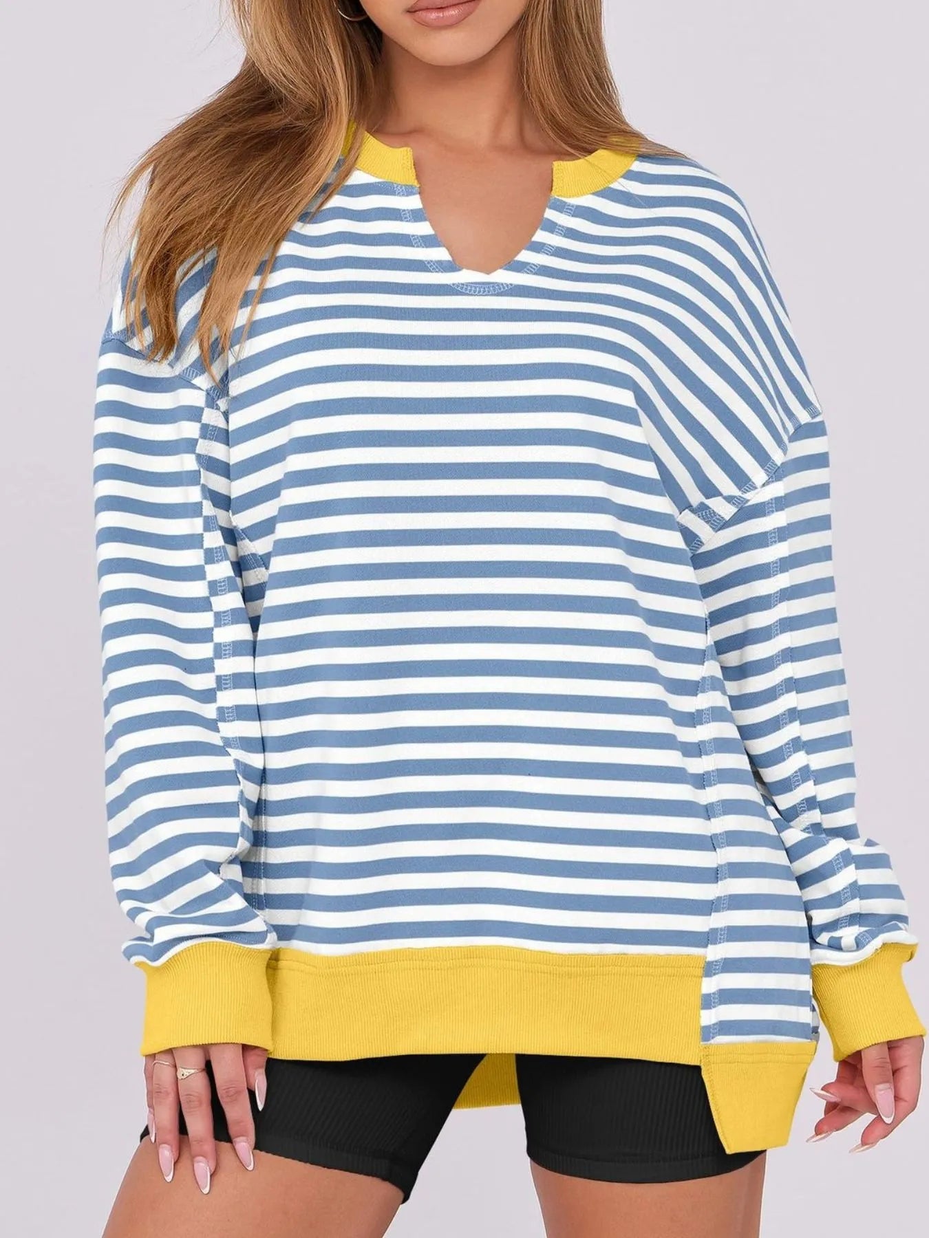 Blue and white striped long-sleeve top with yellow accents worn by a person on a plain background