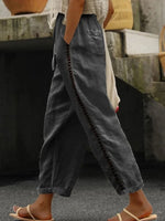 Person wearing dark gray wide-leg pants with decorative stitching, standing on a textured surface.