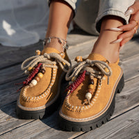 Brown sandals with decorative elements on a wooden surface