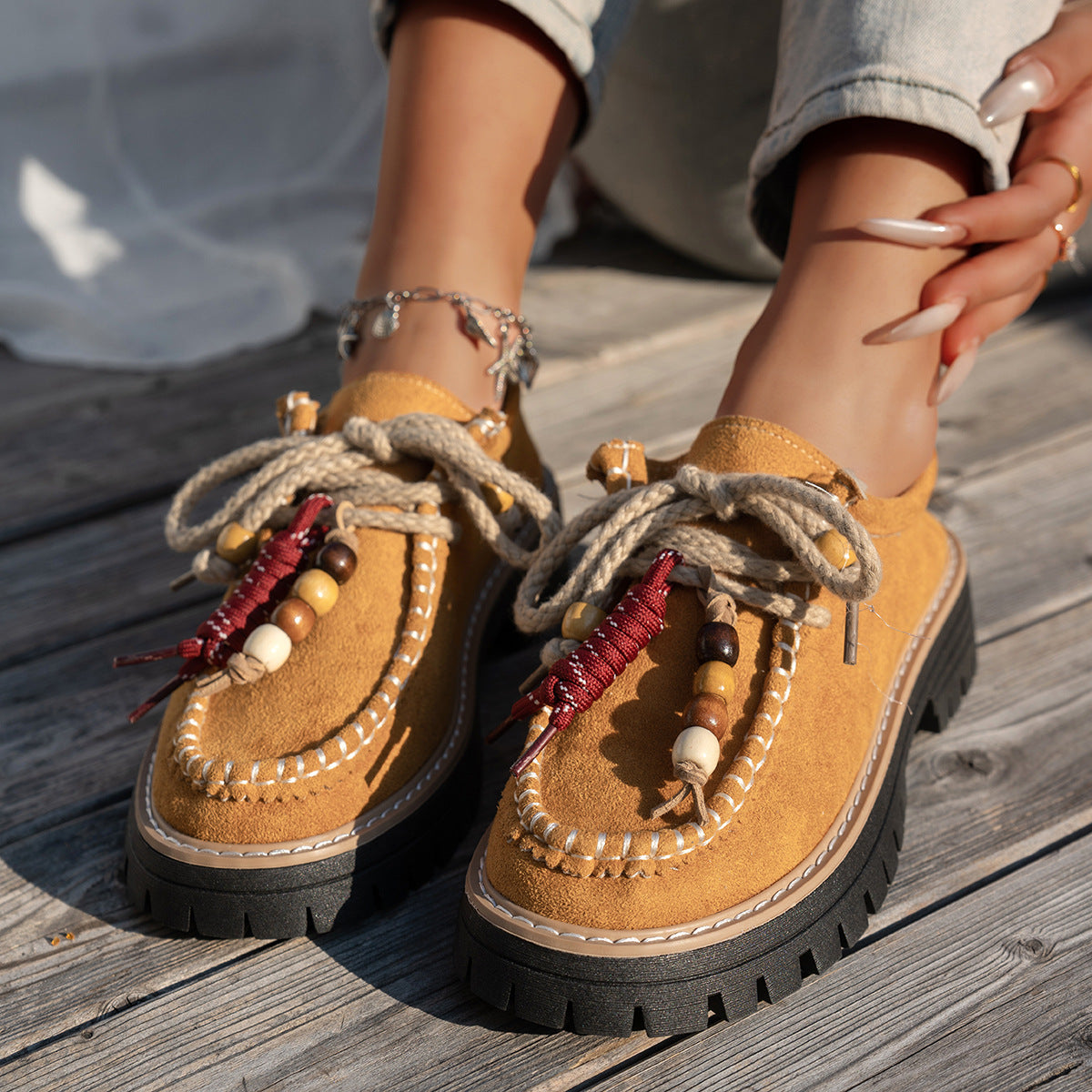 Brown sandals with decorative elements on a wooden surface