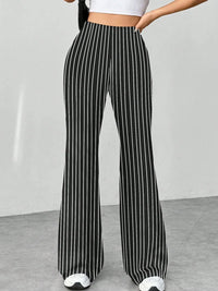 Black and white striped pants worn by a person on a plain background