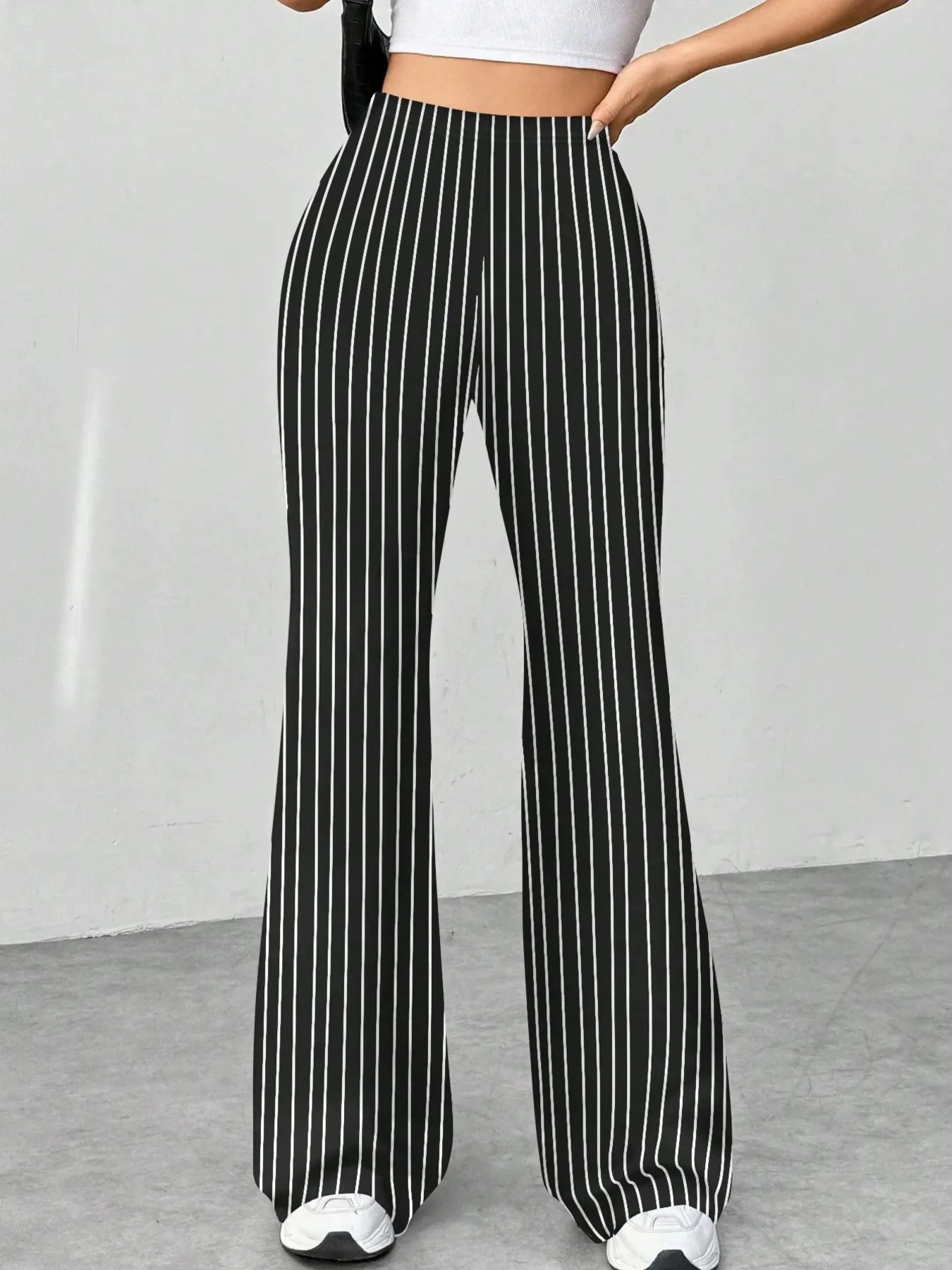 Black and white striped pants worn by a person on a plain background