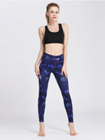 Woman wearing black sports bra and blue galaxy leggings on a white background