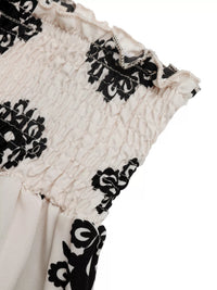 Close-up of a garment with black floral patterns on a white background