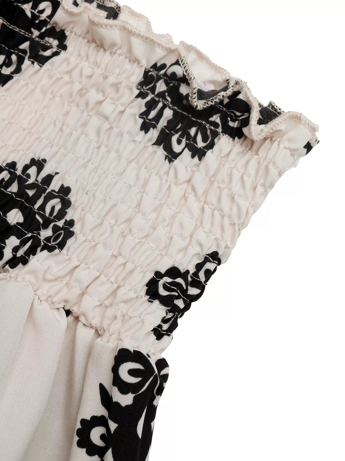 Close-up of a garment with black floral patterns on a white background