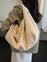 Person wearing a beige oversized bag with a neutral background