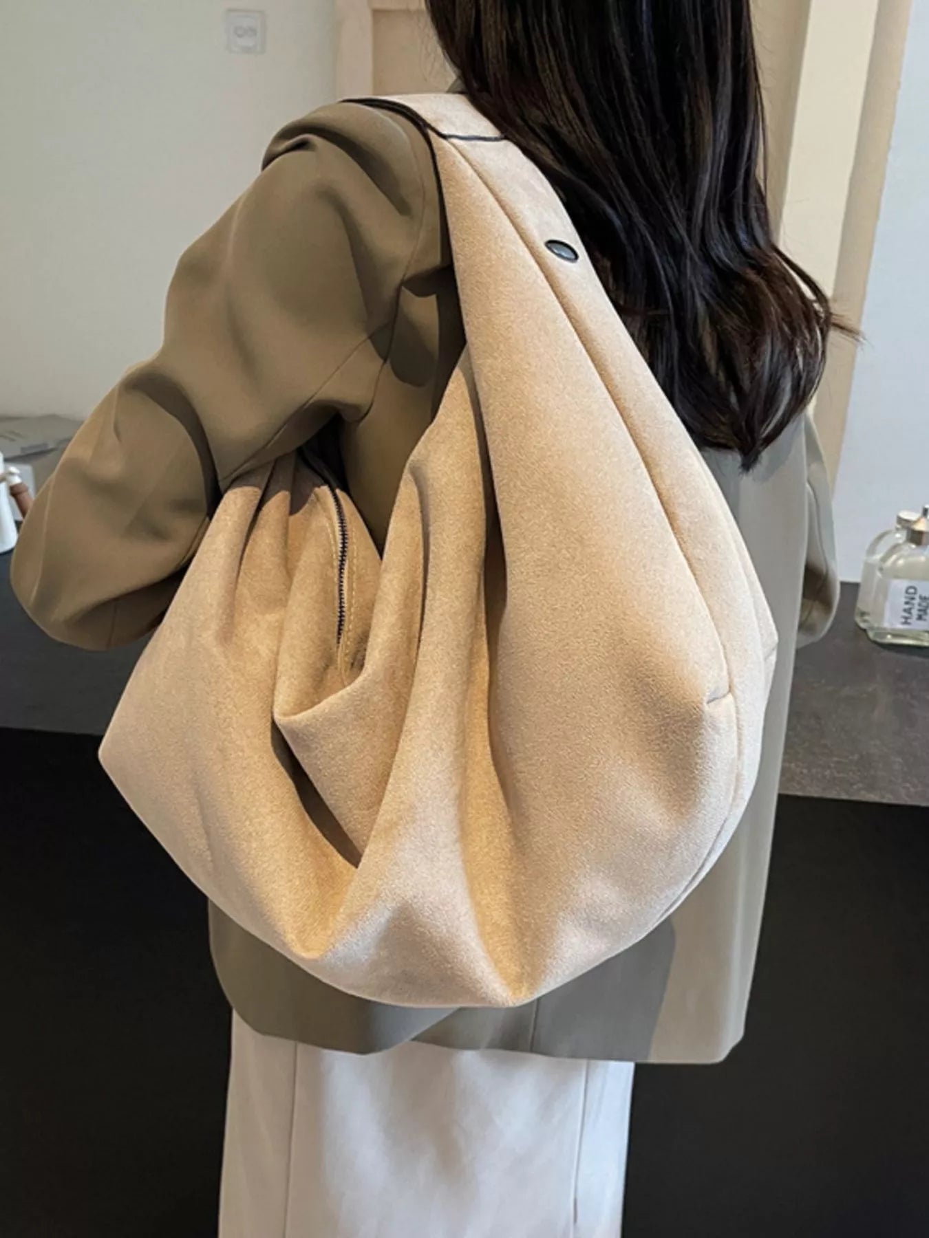 Person wearing a beige oversized bag with a neutral background