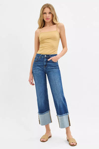 Woman wearing a yellow top and blue jeans on a white background