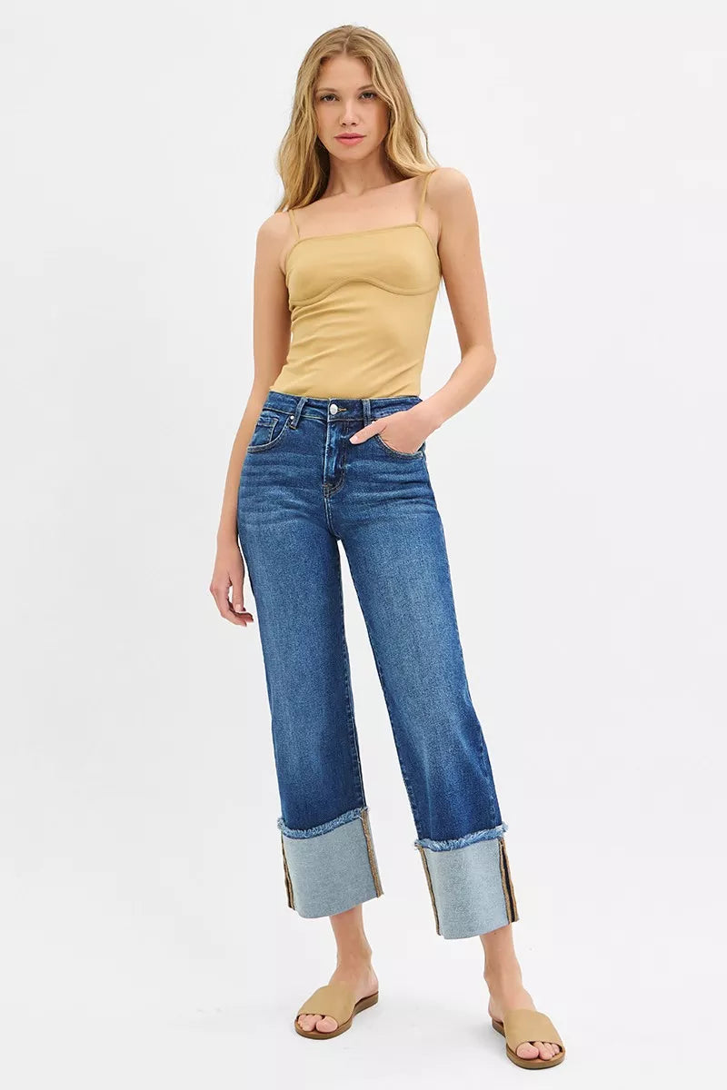 Woman wearing a yellow top and blue jeans on a white background
