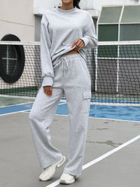 Person wearing a gray sweatshirt and pants on a tennis court