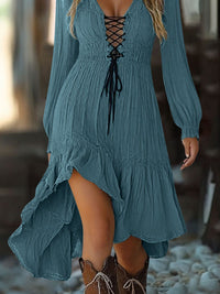 Blue dress with lace-up front and long sleeves worn by a person, standing on a rocky surface.