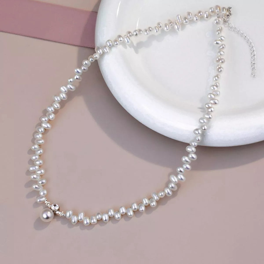 Pearl necklace on a white dish with a pink background