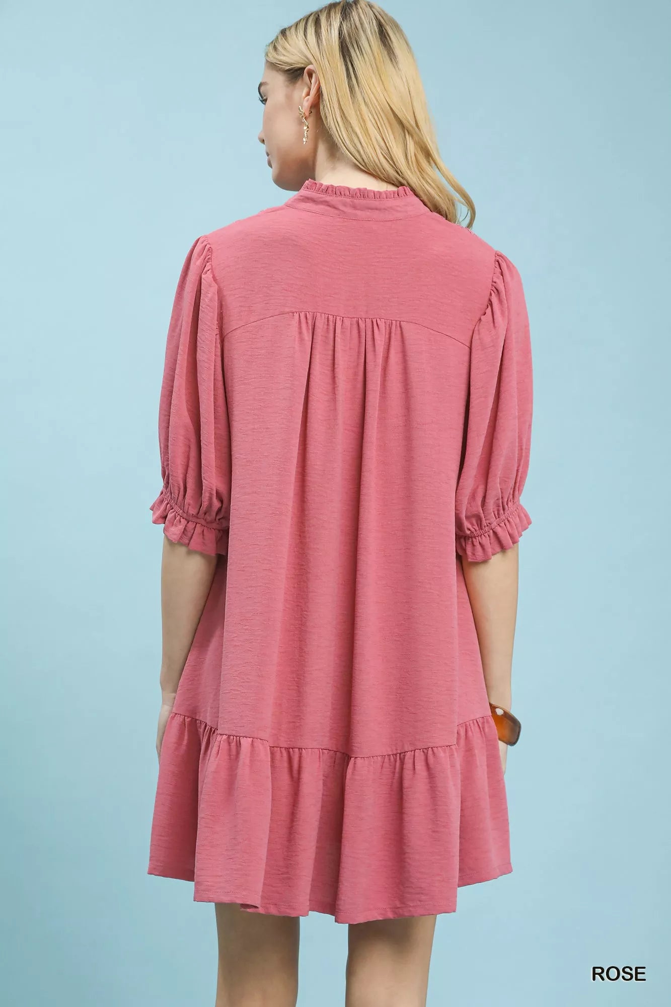 Woman wearing a pink dress against a light blue background