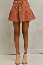 Brown corduroy skirt worn by a person on a neutral background